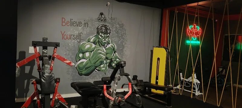 Weights area with a Hulk mural and neon Dimension Gym logo